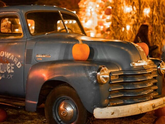 An image of red apples in a plastic bag stored in the back of a blue truck.
